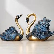 Gold and blue swan figurines on a light background