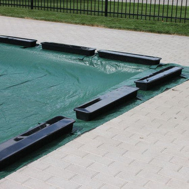 HydroTools water blocks installed on an in-ground swimming pool winter cover to hold it securely in place
